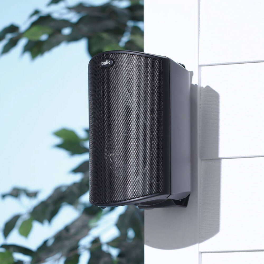 Polk Audio Atrium 4 Outdoor Speaker Polk outdoor wall-mounted speaker on a white exterior wall with a black perforated grille.