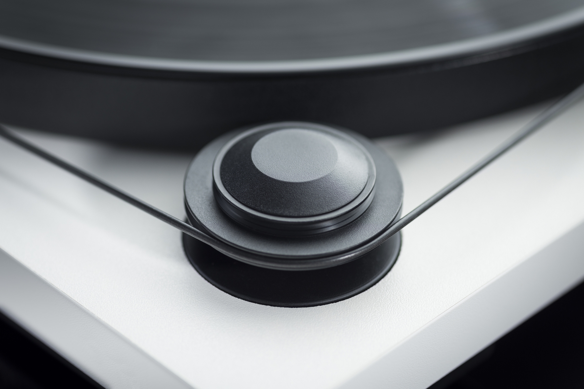 Pro-Ject Primary E Turntable With Om Cartridge Close-up of a textured black control knob on a silver turntable with a vinyl record platter in the background