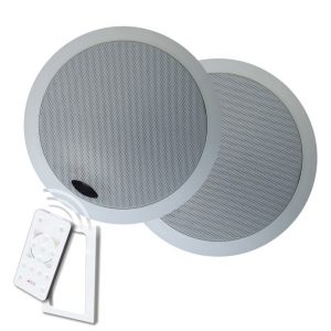 Two Forte A-BUS ABD-C6 in-ceiling loudspeakers with a round, silver design are installed side by side. A white remote control with colored buttons is pointed at the speakers, sending a signal toward them.