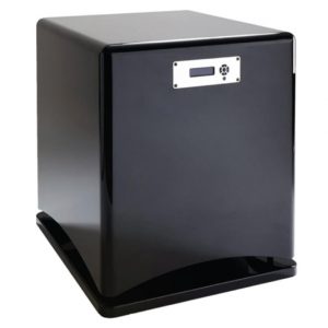 A black, box-shaped Cabasse Santorin 38 electronic device with a small display panel and vent on the front, placed on a flat base.