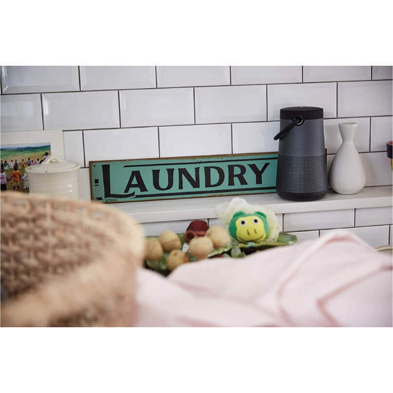 Bose Soundlink Revolve+ Bluetooth Speaker Turquoise vintage laundry sign on a shelf beside a black wireless speaker and white vases