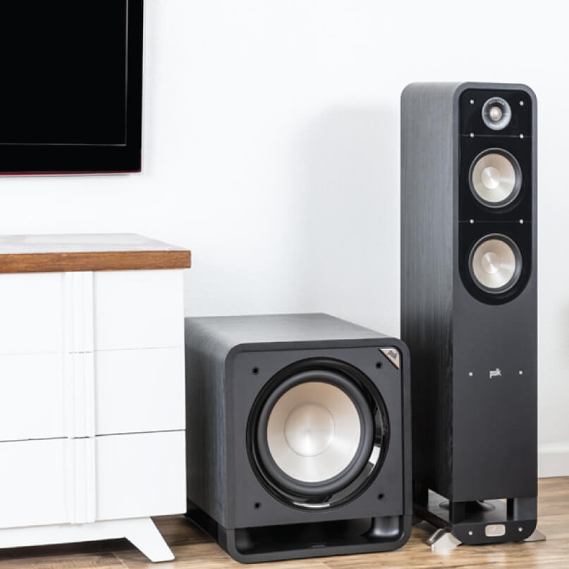 Polk Audio Hts 12 Polk floor-standing speaker with dual woofers and a tweeter, paired with a square subwoofer in a modern living room.