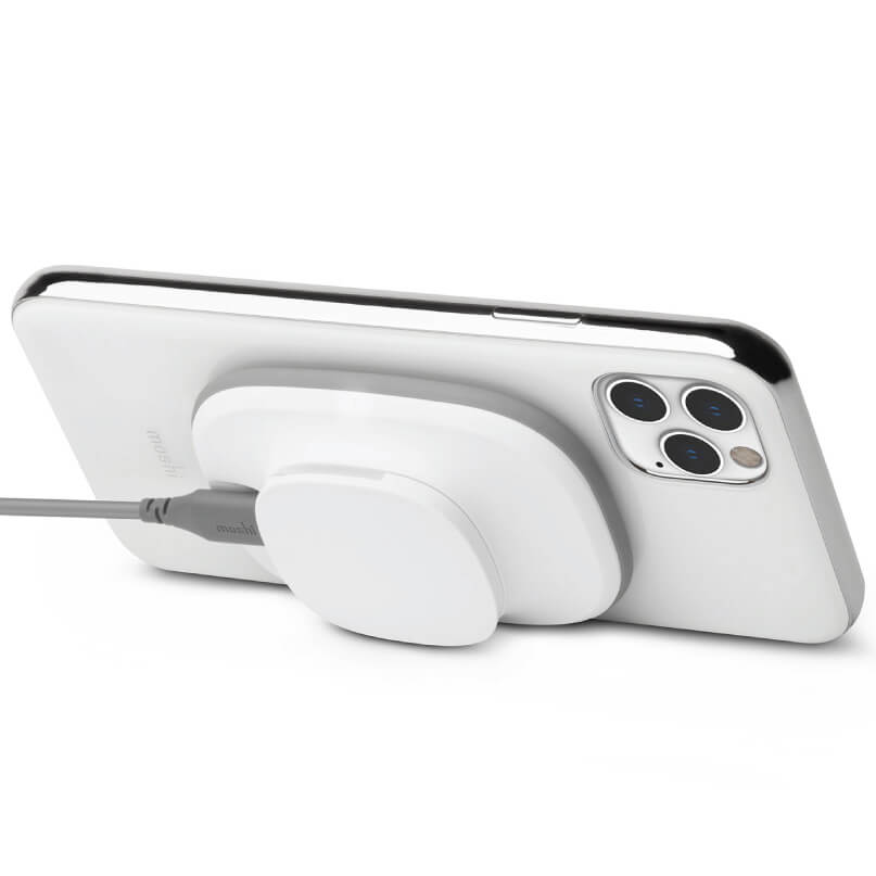 Moshi Snapto Magnetic Wireless Charger W/ Wall Mount Kit (Grey) White iphone with triple-camera back mounted on a circular white desk charging stand.