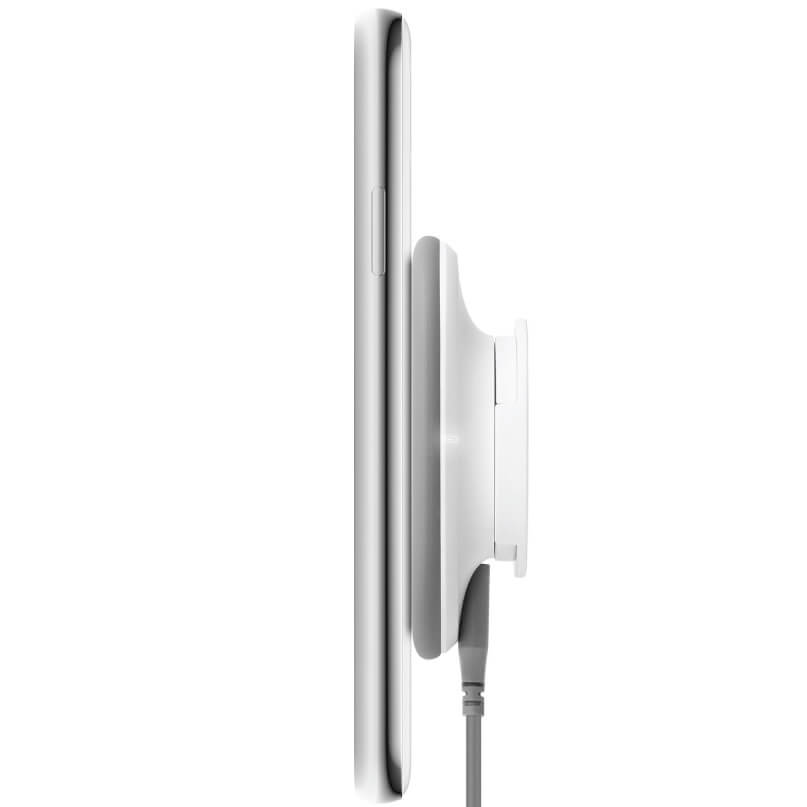 Moshi Snapto Magnetic Wireless Charger W/ Wall Mount Kit (Grey) Side view of a silver smartphone attached to a white wireless charging cradle with a cable.