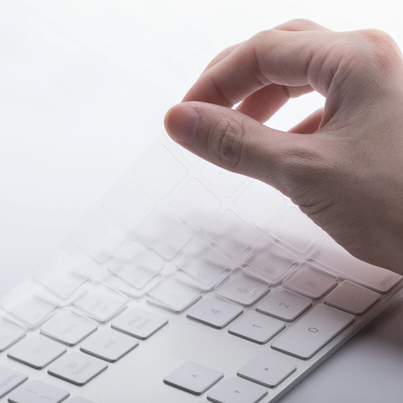 Moshi Clearguard Mk - Apple Keyboard With Keypad Hand applying a transparent keyboard protector onto a white wireless keyboard.