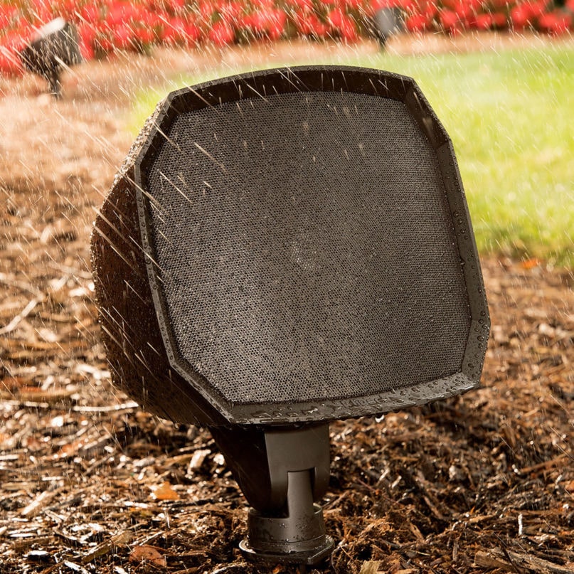 Klipsch Pro-500T-Ls Landscape Satellite Outdoor speaker on a stake with a black octagonal enclosure and mesh grille in garden mulch.