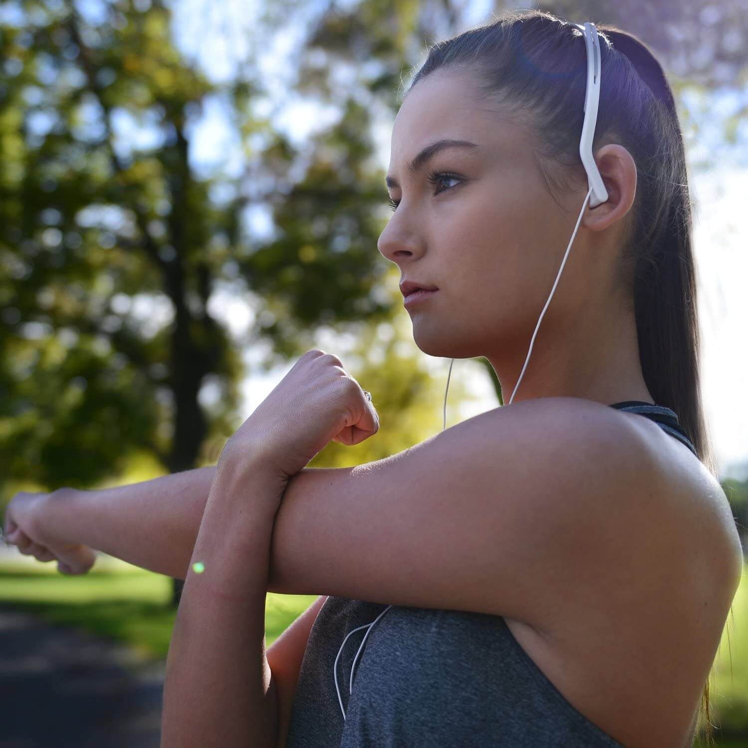 Koss Kph14 On Ear Headphones Young woman wearing white wired earphones outdoors while stretching her arms.