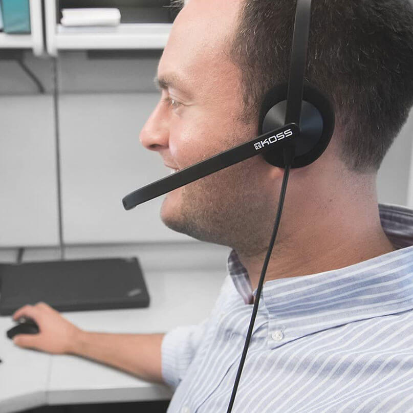 Koss Cs195 Communication Headset/Headphones Koss branded over-ear headset with boom microphone worn by a man at a desk