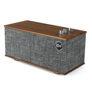 Kapsul portable Bluetooth speaker with wooden top, gray fabric body, and metal knobs on the top.