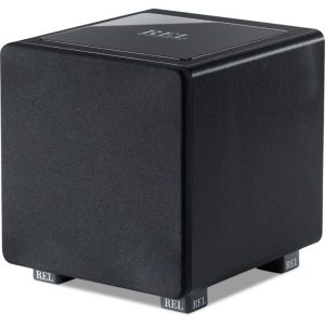 REL subwoofer, compact black cube with fabric front grille, glossy top, and branded feet labeled REL.