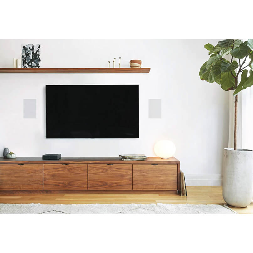 Sonos In-Wall Speaker (Pair) Living room with wall-mounted flat-screen tv above a long wooden media console and a large potted plant.