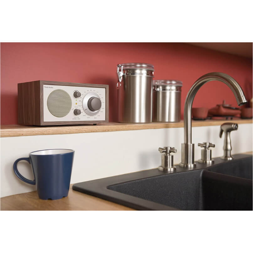 Tivoli Audio Model One Am/Fm Table Radio Retro wooden radio with silver front panel and large dial sits on a wooden shelf beside stainless steel canisters.
