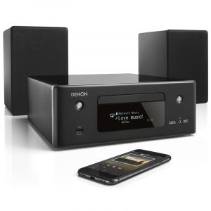 Denon Ceol network music system with CD slot, two satellite speakers, and a smartphone streaming music.