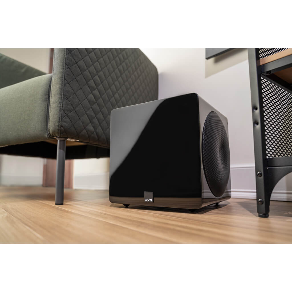 Svs 3000 Micro Subwoofer Svs subwoofer with glossy black front and large circular woofer, placed on a wooden floor beside a quilted sofa.