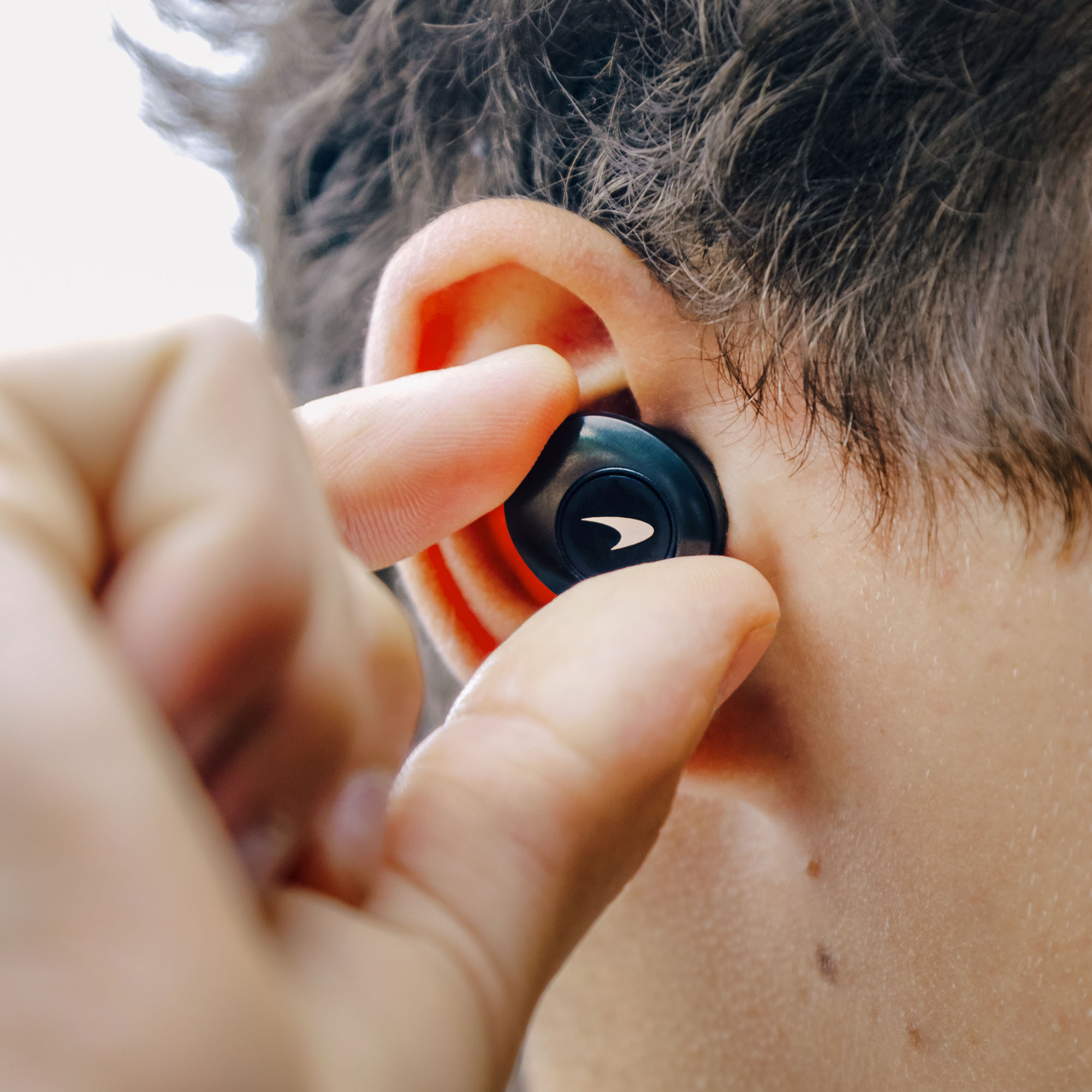 Klipsch Mclaren T5 Ii True Wireless Anc Earphones Close-up of a black wireless earbud with orange accent and white symbol near the ear.