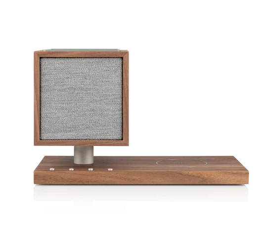 Tivoli Audio Revive Bluetooth Speaker With Wireless Charging Pad And Lamp Wooden speaker with square fabric grill mounted on a vertical wooden frame atop a rectangular base.