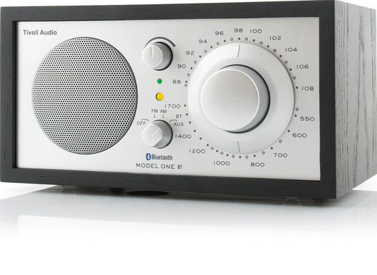 Tivoli Audio Model One Bt Bluetooth / Am / Fm Table Radio Tivoli audio model one bt tabletop radio with large tuning dial, round speaker grille, and woodgrain cabinet.