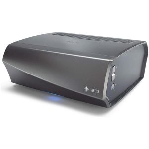 Denon HEOS wireless music streamer in dark gray curved chassis with vented top, front panel controls, blue LED indicator.