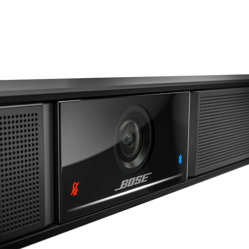 Bose Videobar Vb1 Bose video bar with built-in camera, microphone mute indicator, blue bluetooth icon, glossy front panel, and side speaker grilles.