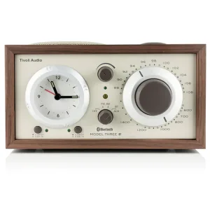 Tivoli Audio Model Three BT compact tabletop radio with white front, clock dial left, large tuning dial right, wood frame.
