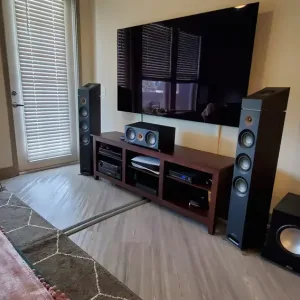 Home theater setup with a large flat-screen TV, tall floor-standing speakers, center channel, subwoofer, and media cabinet.