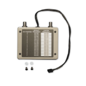 Compact electronic frequency selector module with a hex-position chart and default and custom frequency tables, connected to a black cable.
