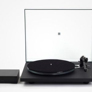 Black turntable with a transparent lid, matte plinth, tonearm on the right, and a separate black preamp on the left.