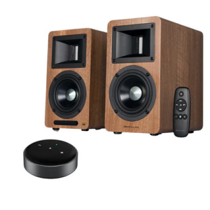 Pair of wood veneer bookshelf speakers with black drivers and a remote, alongside a circular black wireless puck.