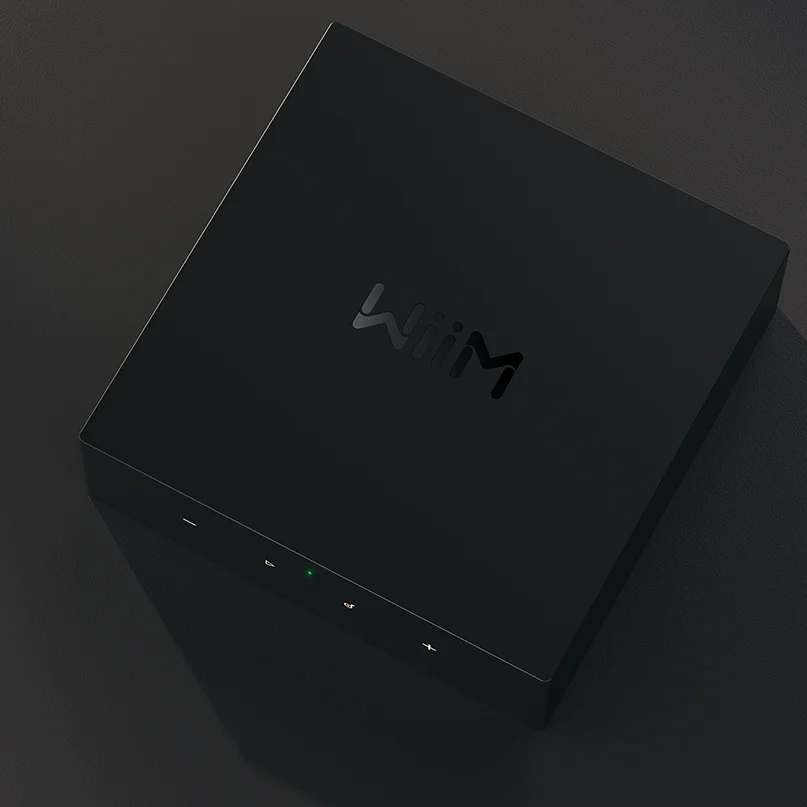 Wiim Ci Mod S Audio Streamer For Custom Installation Black square streaming media player with subtle logo on lid and green front led indicator.