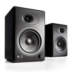Pair of black desktop studio monitor speakers with front-facing woofer and tweeter, volume knob visible.