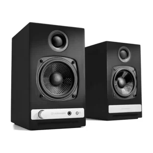 Pair of black Audioengine powered bookshelf speakers with a front silver control panel, large woofer, and top tweeter.