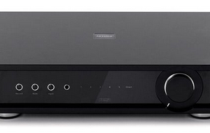 Black stereo integrated amplifier with a large right-side volume knob, five front controls, and a central display.