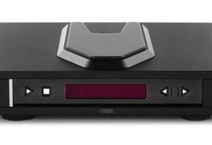 Black compact audio player with red LED display, front controls, left play button, right arrows, and metallic hexagonal top knob.