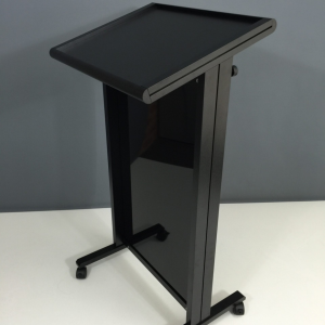 Black metal mobile podium with sloped top and caster wheels.
