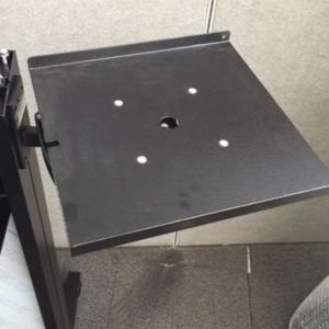 Black metal mounting plate with four small holes around a central larger hole, attached to a supporting frame.