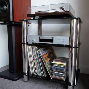 Silcron Steelseries 3 Shelf Hi-Fi Rack – Black Glass Three tier audio rack with turntable on top, silver stereo receiver in the middle, vinyl records and cds below.