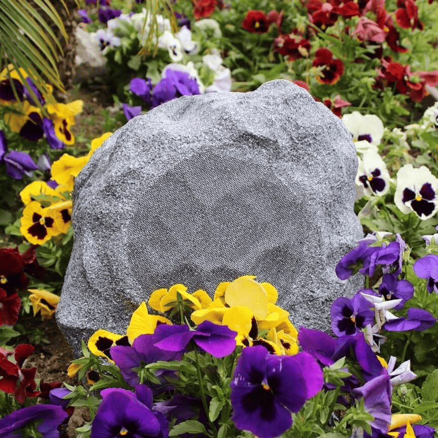 Tgd Audio Ors-602G 6.5″ Outdoor Rock Speaker (Granite) Outdoor rock speaker with a circular grille, nestled among colorful pansies.
