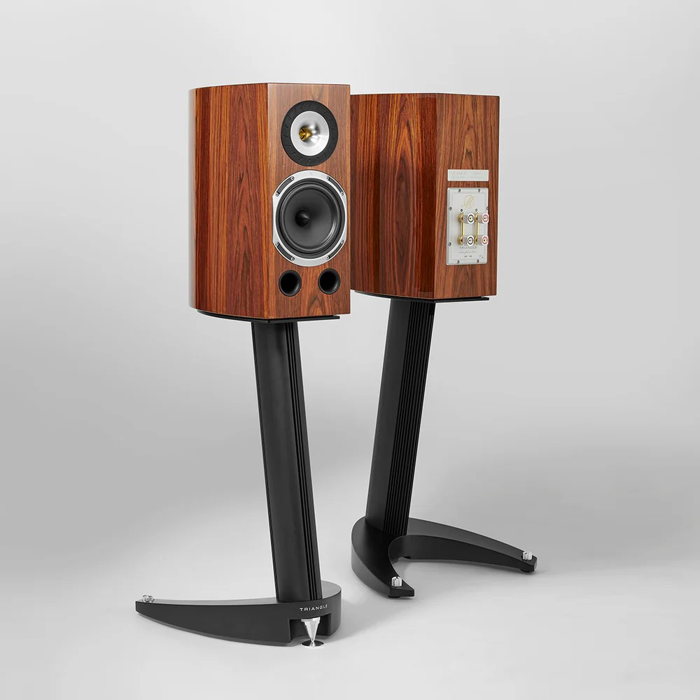 Triangle Magellan Duetto 40Th Premium Bookshelf Speaker Triangle loudspeakers on black curved stands with wood veneer cabinets, showing a tweeter and woofer fronts