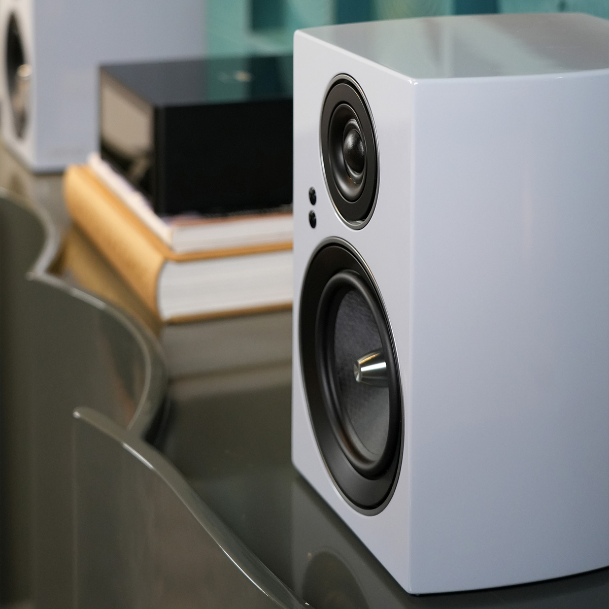 Jamo C707 Pa Active Bookshelf Speaker White bookshelf speaker with dual drivers on glass desk.
