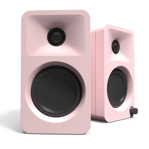 Pair of pink studio monitor speakers with a large black woofer and a small black tweeter in rounded rectangular cabinets; right speaker features a small control knob.