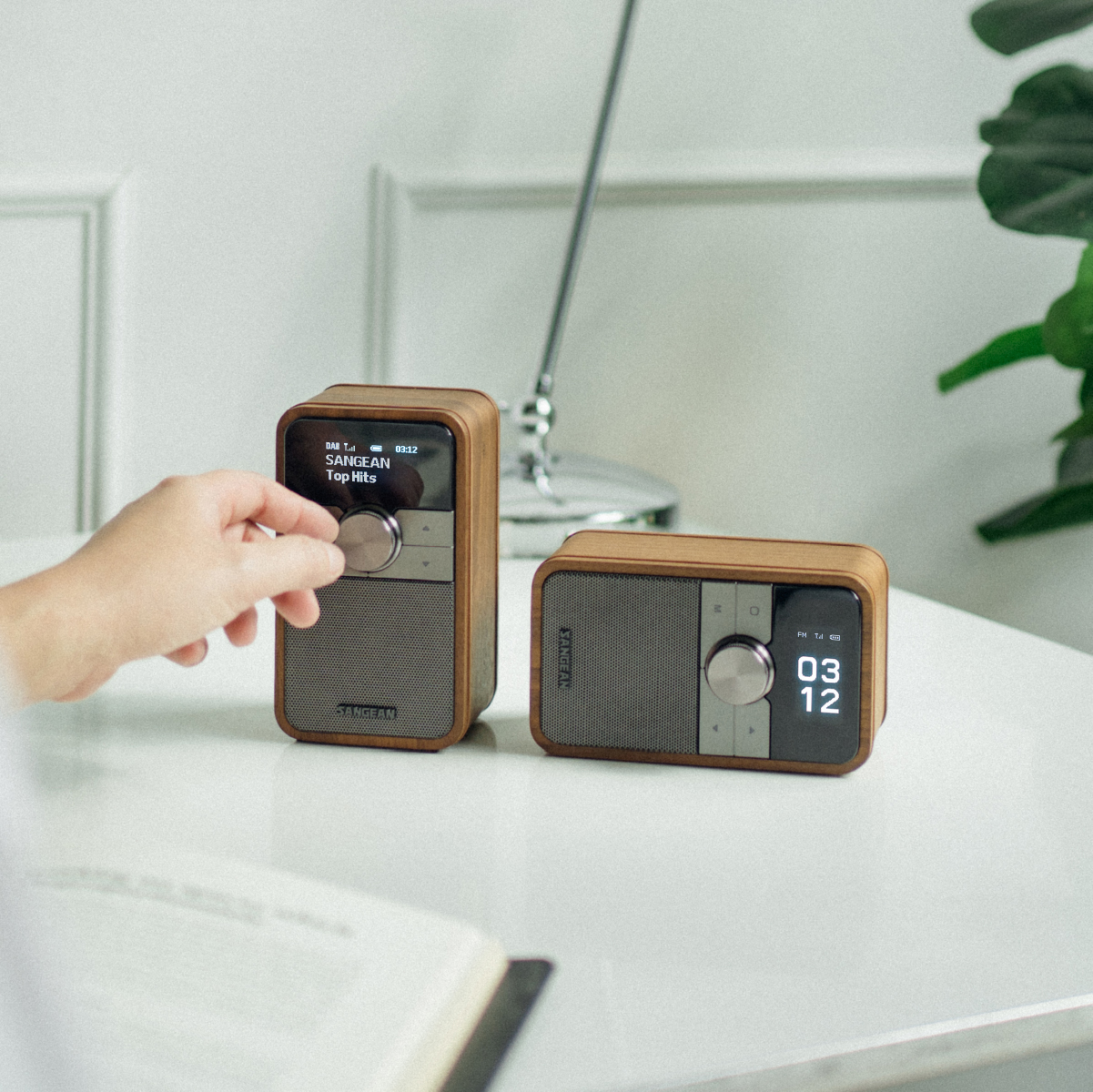 Sangean Ddr-8 Dab+ / Fm-Rds / Bluetooth Wooden Cabinet Radio Two wooden-encased sangean portable radios with gray speaker grills and large round knobs, one upright displaying the song title top hits and the other showing the time 03:12.