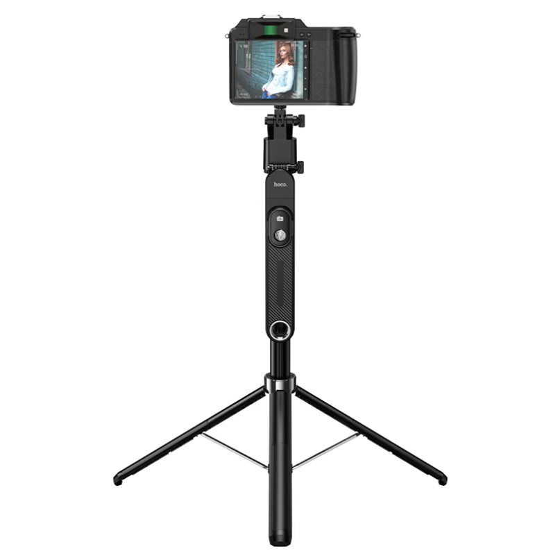 Hoco. Smart Holder “K32 Soporte” Quadropod Face Tracking A hoco. Smart holder “k32 soporte” quadropod face tracking mounted with a camera shows its extendable black legs while the camera screen displays a person posing for a photo.
